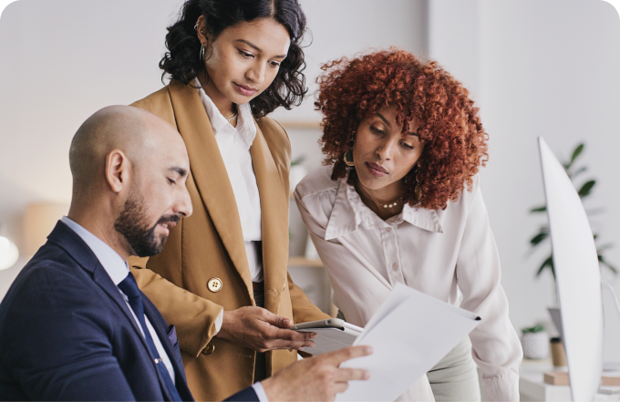 A trio of business colleagues examining paperwork collaboratively in a conference room.