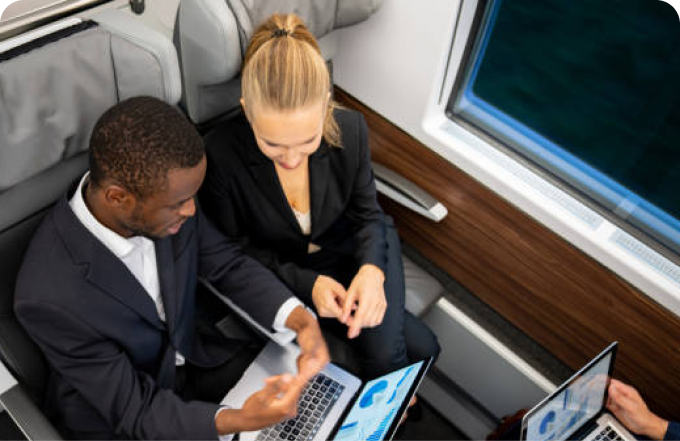 Three colleagues seated on a train, each with a laptop, collaborating on projects during their commute.
