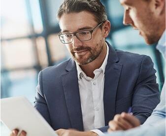 Two business men are reviewing a tablet, collaborating on its details in a business context.