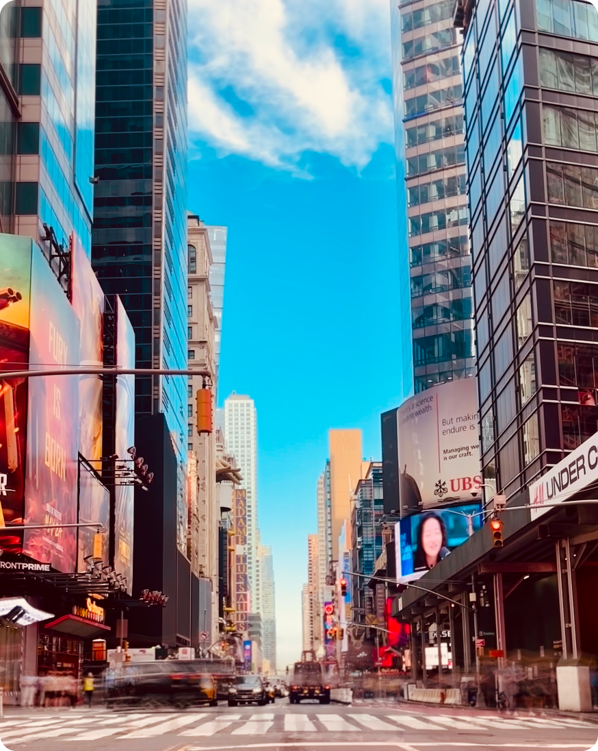 A city street scene with towering buildings and large billboards displaying various advertisements and promotions.