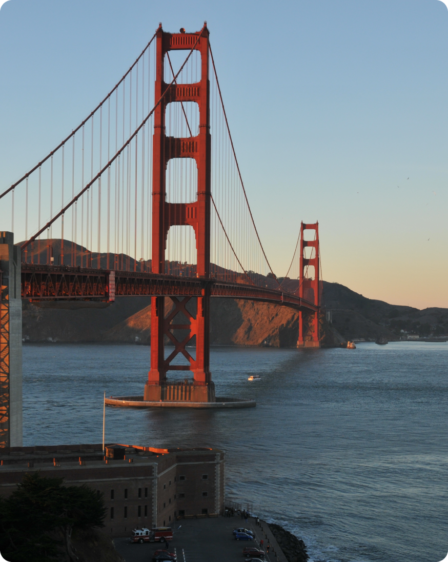 A striking red bridge connects two landmasses, standing out prominently in the natural scenery.